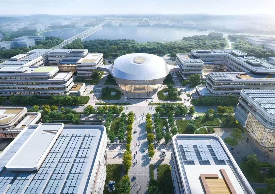 An aerial view of a training campus around a domed field house, a lake beyond